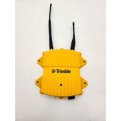 Top view of a yellow Trimble SNR434 dual-band radio modem with both 450 MHz and 2.4 GHz antennas attached.