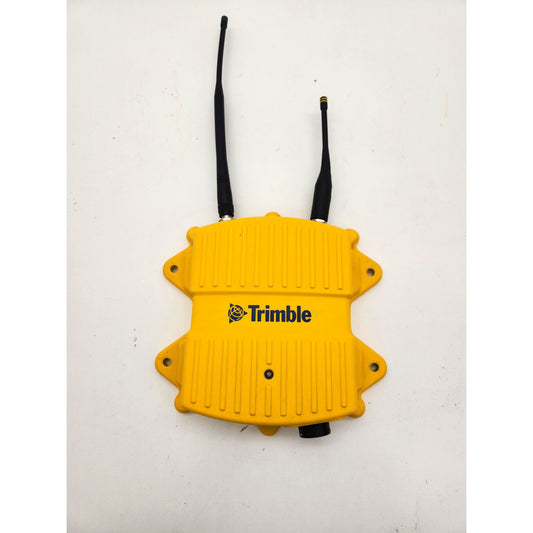Top view of a yellow Trimble SNR434 dual-band radio modem with both 450 MHz and 2.4 GHz antennas attached.